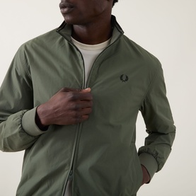 Model wearing Fred Perry Brentham Logo Overshirt in Laurel Wreath Green, showing zip fastening, funnel neck, and embroidered logo detail.