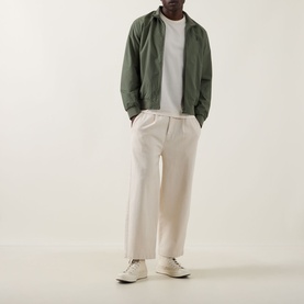 Model wearing Fred Perry Brentham Logo Overshirt in Laurel Wreath Green with zip fastening, styled with cream trousers and white trainers.