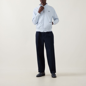 Model wearing Fred Perry Dusky Blue Casual Jacket with zip-up collar, styled with navy wide-leg trousers and dark loafers.