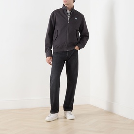 Model wearing Fred Perry Laurel Wreath Harrington Jacket in Anchor Grey, zip fastening, ribbed hem, styled with dark jeans and white trainers.
