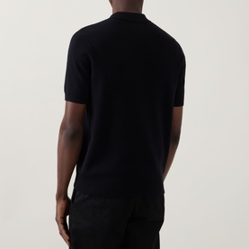 Model wearing Fred Perry Panel Detail Knitted Polo Shirt in Black, rear view showing short sleeves, ribbed trims and fine-knit finish.