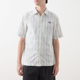 Model wearing Fred Perry Seersucker Check Shirt in Ecru, short sleeves, two-tonal check, embroidered laurel wreath, styled with dark trousers