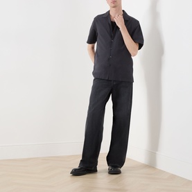 Model wearing Fred Perry Anchor Grey casual shirt with short sleeves and camp collar, styled with matching dark wide-leg trousers and black loafers.