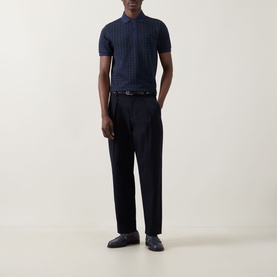 Model wearing Fred Perry Geometric Print Laurel Logo Polo Shirt in Twilight Navy, styled with black tailored trousers and loafers