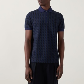 Model wearing Fred Perry Geometric Print Laurel Logo Polo Shirt in Twilight Navy with all-over geometric print and ribbed collar.
