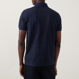 Model wearing Fred Perry Geometric Print Laurel Logo Polo Shirt in Twilight Navy, rear view showing all-over geometric print and ribbed cuffs