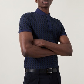 Model wearing Fred Perry Geometric Print Laurel Logo Polo Shirt in Twilight Navy, styled with black trousers and belt.