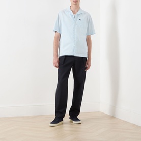 Model wearing Fred Perry Light Ice casual shirt with camp collar, paired with black trousers and navy slip-on shoes.