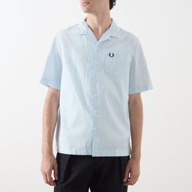 Model wearing Fred Perry Light Ice casual shirt with camp collar, short sleeves, and embroidered logo, styled with black trousers.