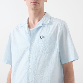Model wearing Fred Perry Casual Shirt in Light Ice, short-sleeve seersucker cotton with camp collar and embroidered laurel wreath logo.