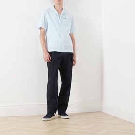 Model wearing Fred Perry Light Ice casual shirt with navy trousers and navy canvas shoes.
