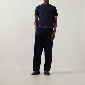 Model wearing Fred Perry Navy Crew Neck T-Shirt with tipped cuffs, styled with navy trousers and a brown leather belt.
