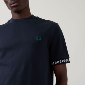 Model wearing Fred Perry Navy Crew Neck T-shirt with tonal laurel wreath logo and checkerboard trim at cuffs.
