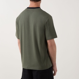 Model wearing Fred Perry Meyba Ringer T-Shirt in Laurel Wreath Green, back view, with black contrast collar and short sleeves.