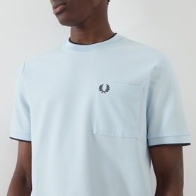 Model wearing Fred Perry Light Ice crew neck T-shirt with chest pocket, laurel wreath logo, and tipped collar detail in cotton.