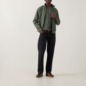 Model wearing Fred Perry Ringer Laurel Wreath T-Shirt in Laurel Wreath Green, styled with an olive zip-up jacket, dark jeans and brown trainers.