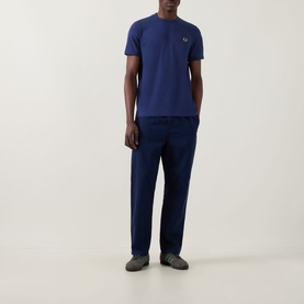 Model wearing Fred Perry Ringer Laurel Wreath T-Shirt in French Navy, styled with navy trousers and grey shoes.
