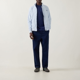 Model wearing Fred Perry Ringer Laurel Wreath T-Shirt in French Navy, styled with a light blue zip-up jacket and navy trousers.
