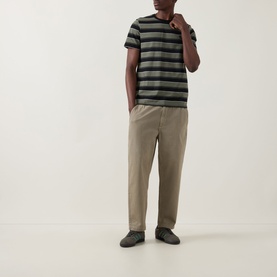 Model wearing Fred Perry Black Striped Crew Neck T-Shirt in cotton, styled with taupe trousers and dark trainers.