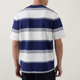 Model wearing Fred Perry Heavy-Striped Laurel Wreath Logo T-Shirt in Ecru, showing rear view with navy bold horizontal stripes and short sleeves.