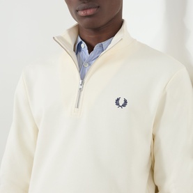 Model wearing Fred Perry Ecru cotton half-zip sweat with French Navy laurel wreath logo, styled with a light blue collared shirt underneath.