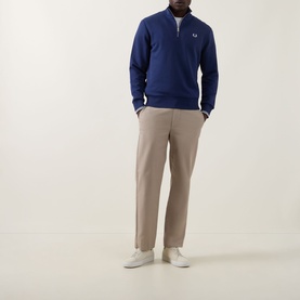Model wearing Fred Perry Wreath Logo Half-Zip Sweatshirt in French Navy, styled with stone chinos and white trainers.