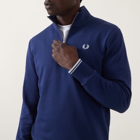 Model wearing Fred Perry Wreath Logo Half-Zip Sweatshirt in French Navy, showing funnel neck, half-zip fastening and embroidered laurel wreath logo.