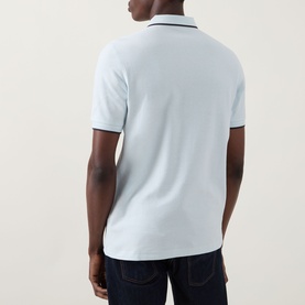 Model wearing Fred Perry Laurel Logo Crepe Piqu&eacute; Polo Shirt in Light Ice, back view, twin tipped collar, paired with dark jeans