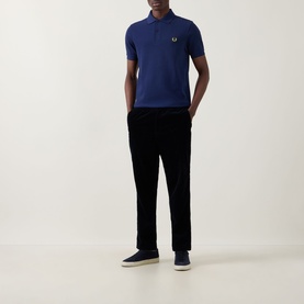 Model wearing Fred Perry Twin Tipped Polo Shirt in French Navy with black trousers and navy canvas shoes.