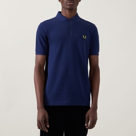 Model wearing Fred Perry Twin Tipped Polo Shirt in French Navy with Citron Laurel Wreath logo, short sleeves and two-button placket