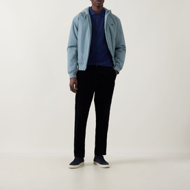 Model wearing Fred Perry Twin Tipped Polo Shirt in French Navy, styled with a light blue zip-up jacket and black trousers.