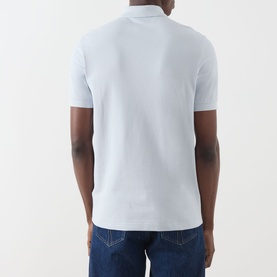Model wearing Fred Perry Twin Tipped Polo Shirt in Dusty Blue, back view, styled with blue jeans.