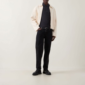 Model wearing Fred Perry Twin Tipped Polo Shirt in Anchor Grey/Light Ice, styled with cream harrington jacket, black jeans and black leather shoes.