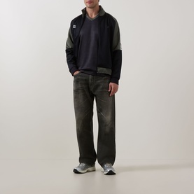 Model wearing Fred Perry Meyba Long-Sleeve T-Shirt in Black with ribbed cuffs and laurel wreath logo, styled with dark wide-leg jeans.