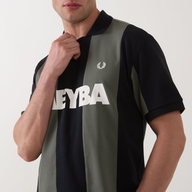 Model wearing Fred Perry Meyba Cut & Sew Polo Shirt in black, colour-block design with khaki panel and graphic logo print