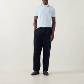 Model wearing light blue polo shirt with tipped collar, styled with navy wide-leg trousers and dark loafers