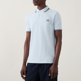 Model wearing pale blue Fred Perry polo shirt with navy twin tipping on collar and cuffs, embroidered laurel wreath logo