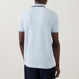Model wearing light blue polo shirt with navy tipped collar and cuffs, styled with navy trousers, back view