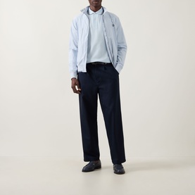 Model wearing light blue zip-up jacket and navy wide-leg trousers, styled with a pale blue polo shirt and dark loafers