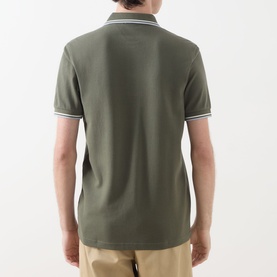 Model wearing Fred Perry Twin Tipped Logo Polo Shirt in Laurel Wreath Green with ecru and dusky blue twin tipped collar and cuffs, back view.