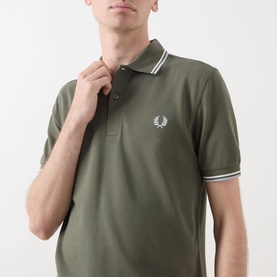 Model wearing Fred Perry Twin Tipped Polo Shirt in Laurel Wreath Green with white tipped collar and cuffs, embroidered laurel logo