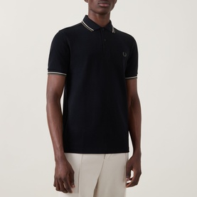 Model wearing Fred Perry Laurel Logo Twin Tipped Polo Shirt in Black with oatmeal tipping, short sleeves and chest logo, styled with stone trousers