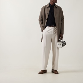 Model wearing Fred Perry Laurel Logo Twin Tipped Polo Shirt in Black/Oatmeal/Laurel Wreath Green, styled with taupe jacket and cream trousers.