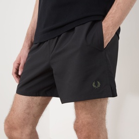 Model wearing Fred Perry Laurel Wreath Swim Shorts in black with embroidered logo, paired with a black T-shirt