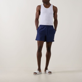 Model wearing Fred Perry Laurel Logo Swim Shorts in French Navy with white vest and grey slides