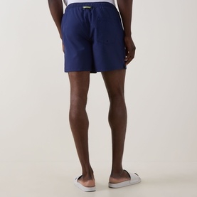 Model wearing Fred Perry Laurel Logo Swim Shorts in French Navy, shown from behind with elasticated waistband and rear patch pocket.