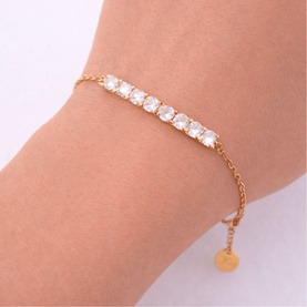 Model with Lynott Jewellery gold-tone bracelet featuring row of clear crystal stones on delicate chain with small disc charm.