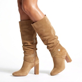 Model wearing Carvela Jackpot Slouch Knee-High Boots in brown suede with block heel and gold-tone crystal stud detail