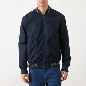 Model wearing Scotch & Soda Reversible Printed Bomber Jacket in Sky Captain, zip front, patch pockets, patterned ribbed collar and hem, styled with