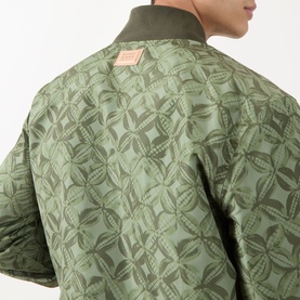 Model wearing Scotch & Soda Reversible Printed Bomber Jacket in Sky Captain, back view showing floral quilted print and ribbed collar trim.